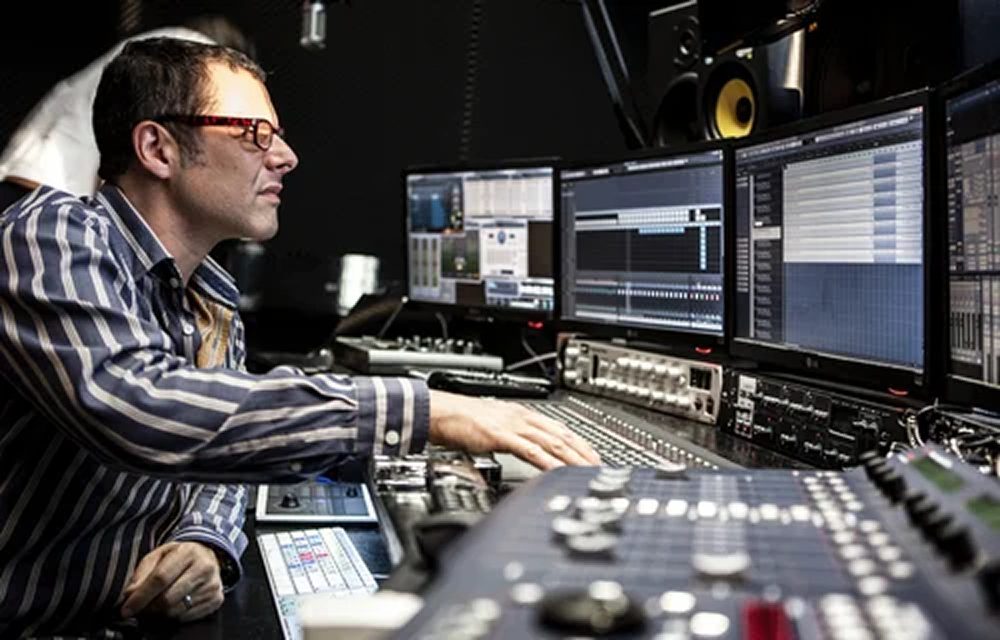 Studio — Recording Session Recording engineer working at a mixing desk in a studio