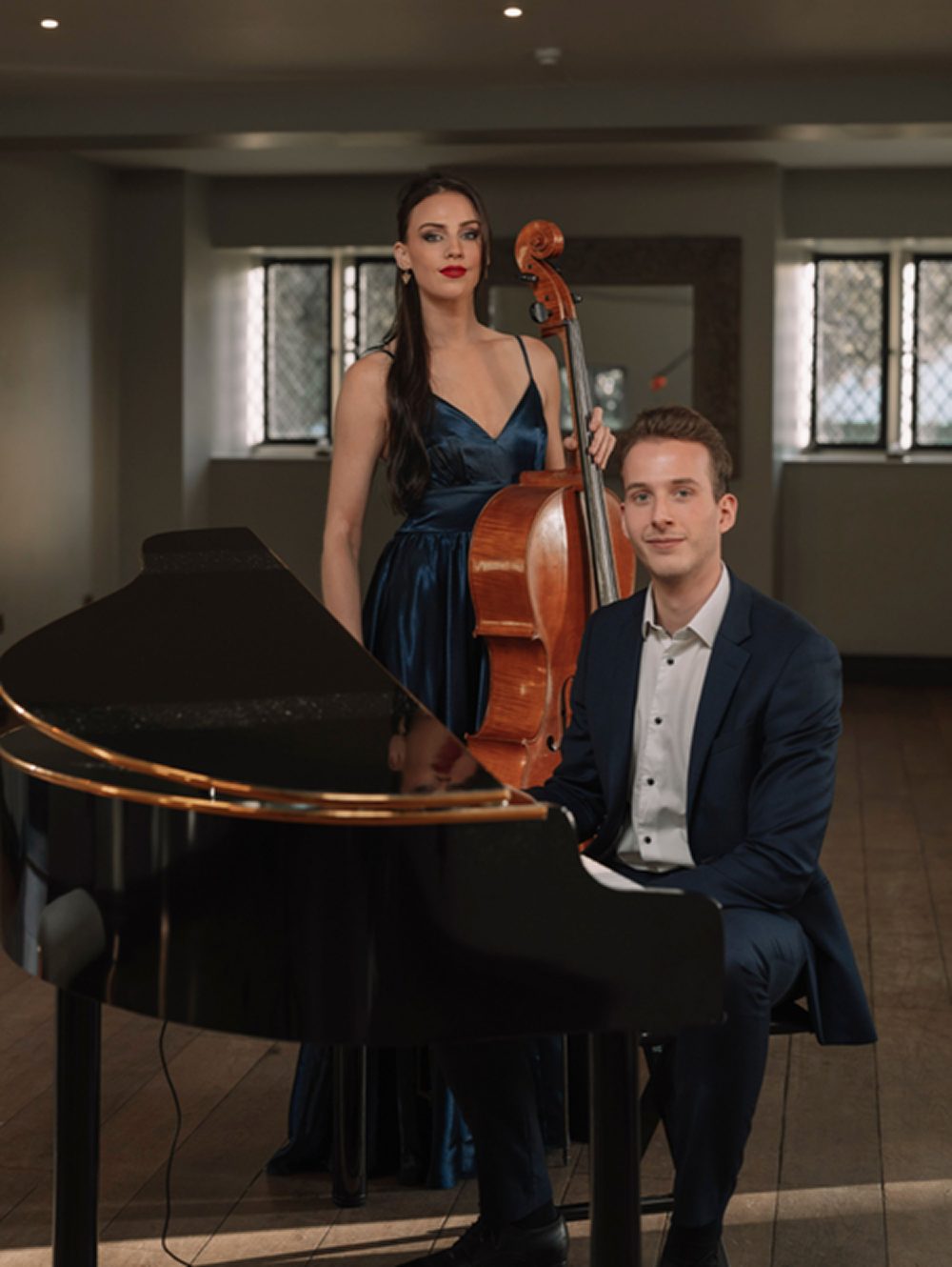 Solos & Duos — Cello and Piano Duo Cello and piano duo posed together indoors