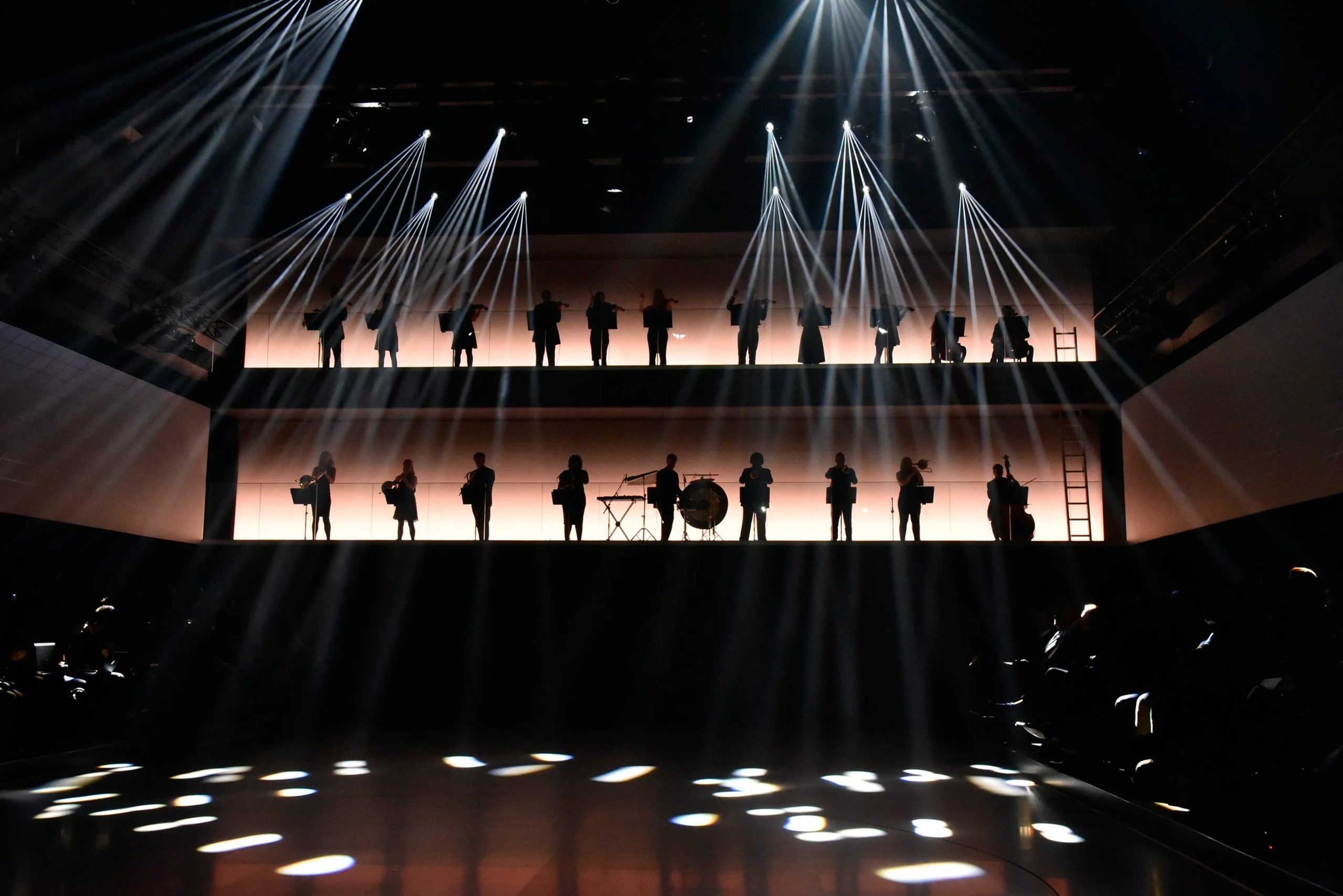Bespoke Orchestral Performance — BMW 7 Series Launch, Munich Urban Soul Orchestra musicians performing in silhouette on two illuminated tiers under beams of white light at a product launch.